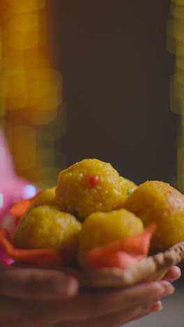 Vertical-Video-Close-Up-Of-Woman-Celebrating-Festival-Of-Diwali-Holding-Dish-Of-Ladoo-1